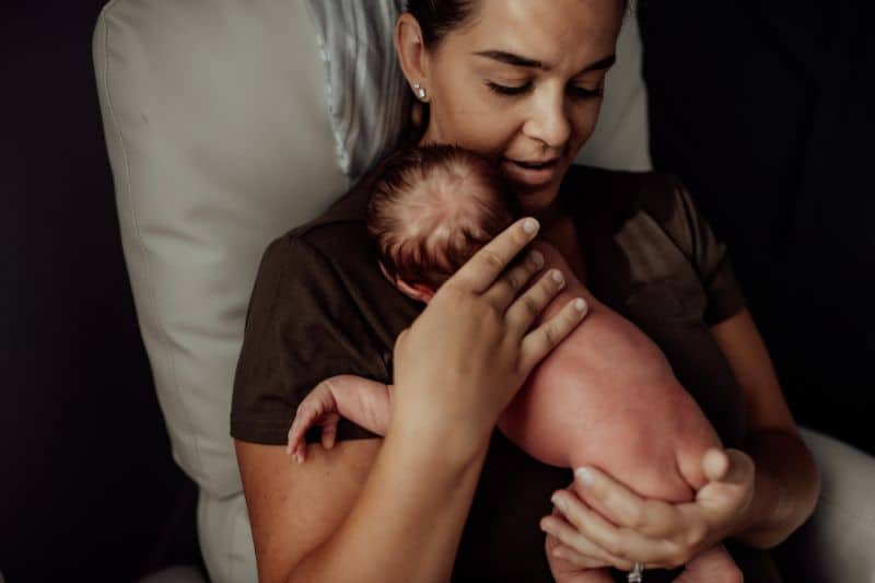 New parent holds a naked newborn baby postpartum
